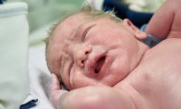 Die Hebamme versorgt das Neugeborene nach der Geburt